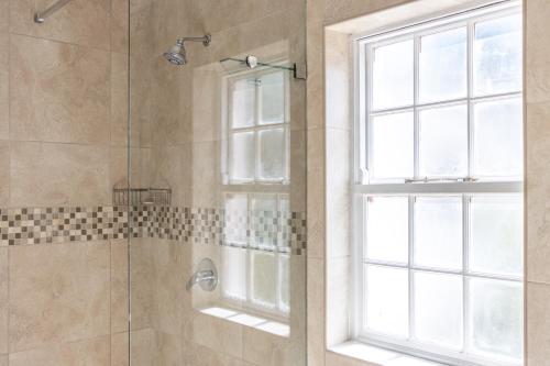 a shower with a glass door and a window at Anoud Manor in Hout Bay