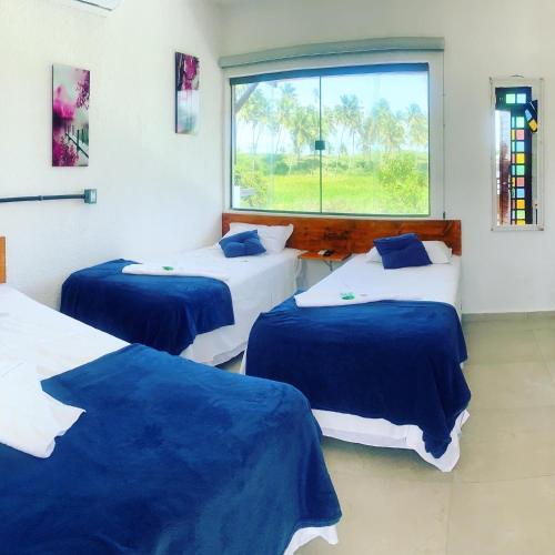 two beds in a room with a window at Pousada Brisa e Mar in Praia do Frances