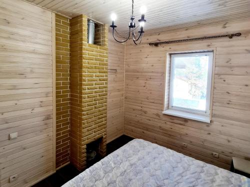 Schlafzimmer mit Ziegelwand und Fenster in der Unterkunft Котедж бiля рiчки село Кудашiвка in Kudashevka