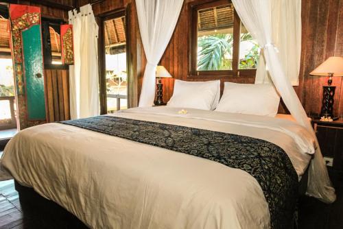 ein Schlafzimmer mit einem großen weißen Bett mit einem Fenster in der Unterkunft Radiant Jepun Villa in Legian