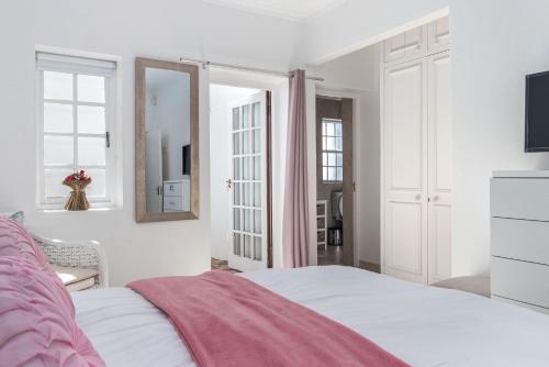 a white bedroom with a bed and a tv at Anoud Manor in Hout Bay