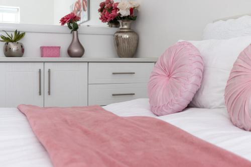a white bed with pink pillows and a dresser at Anoud Manor in Hout Bay