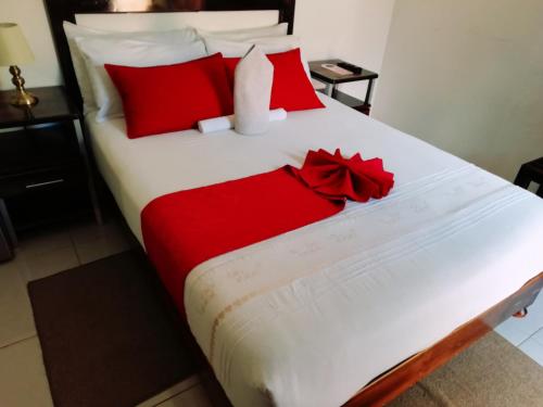 a bed with red pillows and a red bow on it at Mashusha Bed & Breakfast in Gaborone