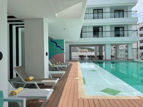 Una piscina con tumbonas junto a un edificio. en 3H Hotel Rodadero SANTA MARTA, en Santa Marta
