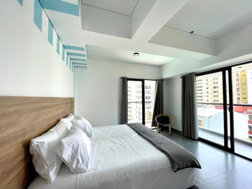 a bedroom with a white bed and large windows at 3H Hotel Rodadero SANTA MARTA in Santa Marta