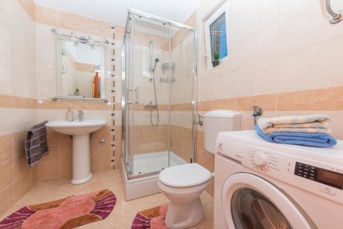 a bathroom with a shower toilet and a washing machine at Holiday home Frane in Slivno
