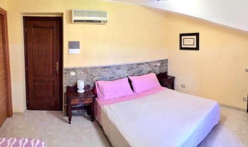 a bedroom with a bed with pink pillows and a table at B & B Casal Pereto in Valmontone