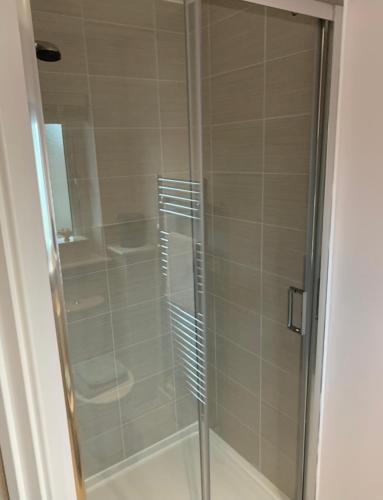 a shower with a glass door in a bathroom at Cop26 3 bedroom house - 10mins walk GLA Airport in Paisley