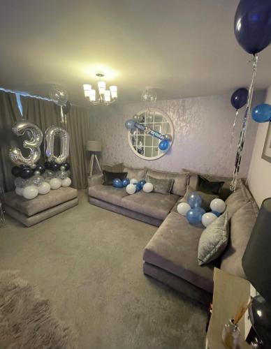 a living room with two couches and balloons at Cop26 3 bedroom house - 10mins walk GLA Airport in Paisley