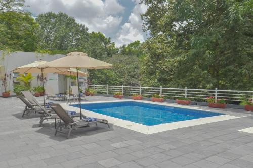 a swimming pool with an umbrella and chairs and a table and an umbrella at HB Córdoba in Córdoba
