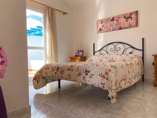 a bedroom with a bed with a floral bedspread and a window at Sol y Mar in Tarajalejo