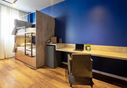 a room with a desk and a bed with a laptop at Swan Generation Porto Alegre in Porto Alegre