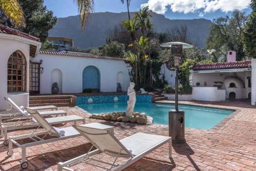 a house with a swimming pool with chairs and a statue at Anoud Manor in Hout Bay