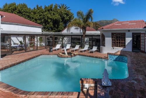 a large swimming pool with chairs and a house at Anoud Manor in Hout Bay