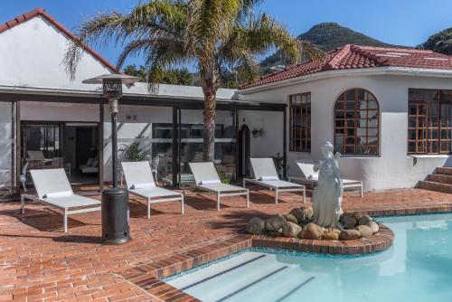 a swimming pool with a statue in front of a house at Anoud Manor in Hout Bay