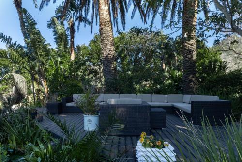 a patio with a white couch and palm trees at Anoud Manor in Hout Bay