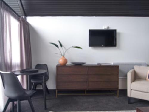 a living room with a couch and a tv on a wall at Hotel Carlton Mill in Christchurch