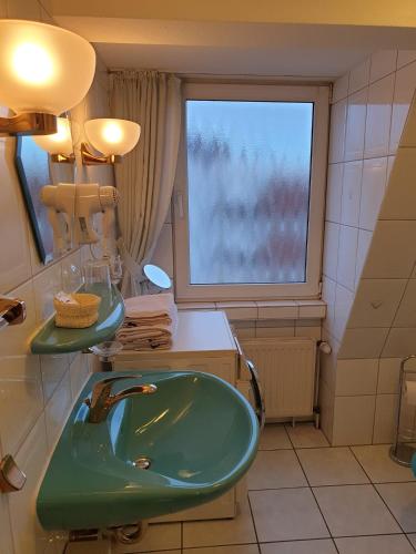 ein Bad mit einem grünen Waschbecken und einem Fenster in der Unterkunft Calabria Nr 3 in Mülheim an der Ruhr