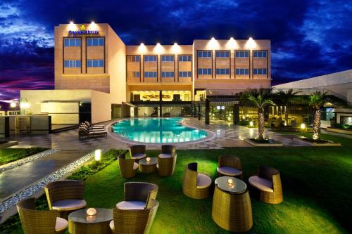 a hotel with a pool and chairs and a building at Golden Tulip Bhiwadi in Dhāruhera