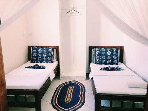 two beds in a room with a rug on the floor at Kelele Square in Zanzibar City