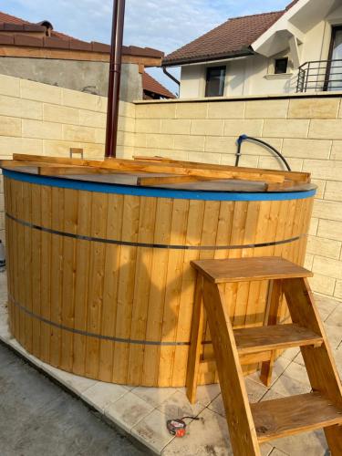 a wooden tub with a wooden bench in front of a building at Casa Andreea in Sînmartin