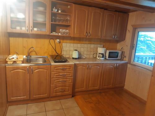 eine Küche mit Holzschränken, einem Waschbecken und einem Fenster in der Unterkunft Villa Victoria in Kamesznica