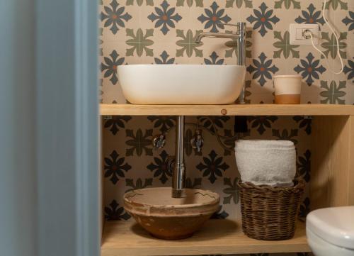 a bathroom with a sink and a bowl on a shelf at La Casetta di Erasmina in Castellana Grotte