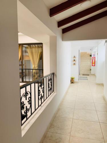 a hallway with white walls and a staircase with black railing at Hostel Casa Zambrano in Popayan