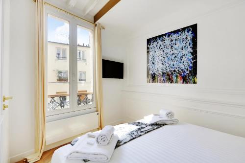a white bedroom with a bed and a window at Pick A Flat's Apartment on rue Montorgueil in Paris