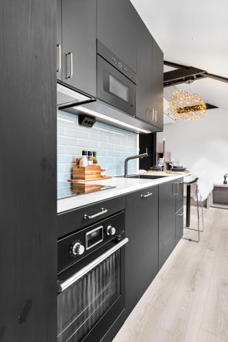 a kitchen with black cabinets and a sink at In the heart of Narvik ! in Narvik