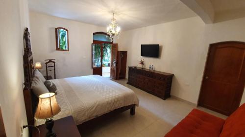 a bedroom with a bed and a dresser and a tv at Casa aroma de café, en el corazón de Coatepec. in Coatepec