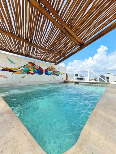 an outdoor swimming pool with a wooden pergola at Playa Nah in Playa del Carmen