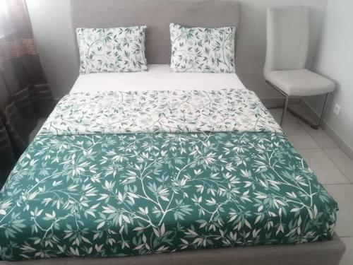 - une chambre dotée d'un lit avec une couverture verte et blanche dans l'établissement Location d'appartement entièrement meublé près de Genève, à Annemasse