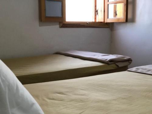 two beds in a room with a window at beachfront house in Taghazout