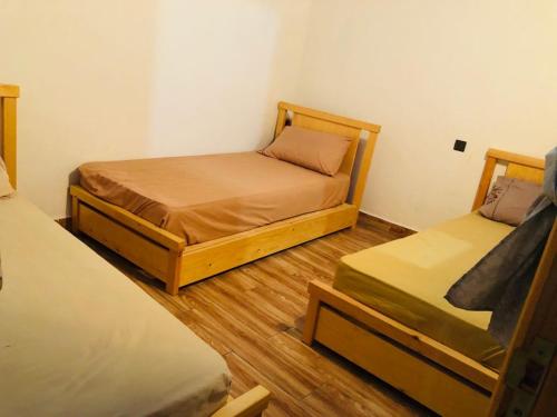 two beds in a small room with wooden floors at beachfront house in Taghazout
