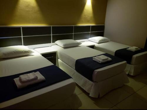 Una habitación de hotel con tres camas en una habitación. en Hotel LLamosas, en Ciudad del Este