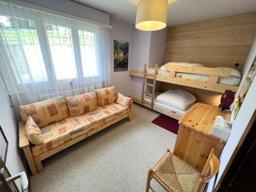 1 Schlafzimmer mit 2 Etagenbetten und einem Sofa in der Unterkunft Bel appartement 3 pièces au pied des pistes de ski in Crans-Montana