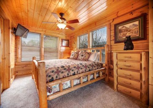 1 dormitorio en una cabaña de madera con 1 cama y ventilador de techo en Beyond Expectations - Pigeon Forge, TN by TS, en Sevierville