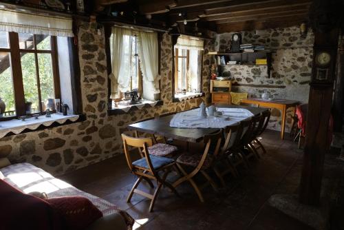 una sala da pranzo con tavolo, sedie e finestre di Старата къща / село Тъжа a Tŭzha