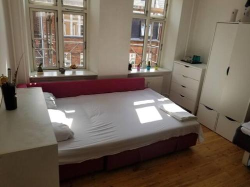 a large bed in a room with two windows at Bright & Cozy Room in Zone 1 in Copenhagen