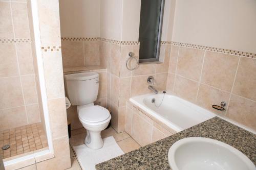 ein Badezimmer mit einem WC, einer Badewanne und einem Waschbecken in der Unterkunft Grayston Exec Apartments in Johannesburg