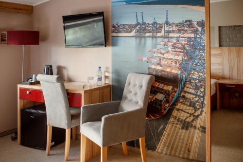 a room with a desk and chairs and a painting of a ship at Kamienica Morska Gdynia in Gdynia