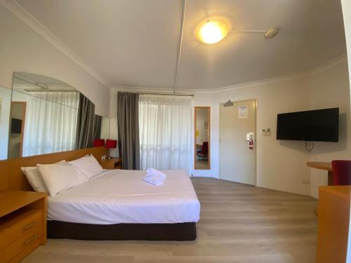 a hotel room with a bed and a flat screen tv at Garden Lodge Sydney Hotel in Sydney