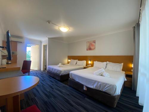 a hotel room with two beds and a table at Garden Lodge Sydney Hotel in Sydney