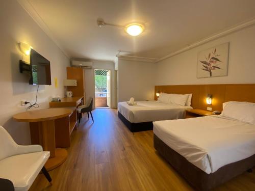 a hotel room with two beds and a desk at Garden Lodge Sydney Hotel in Sydney