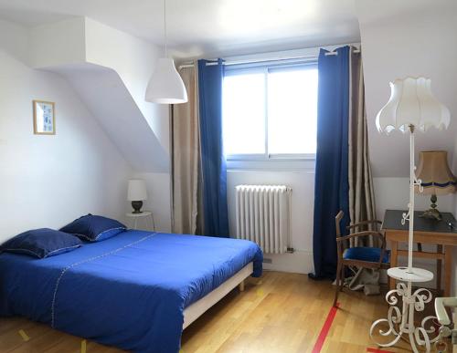 a bedroom with a blue bed and a window at Les Abeilles in Saint-Nazaire