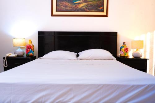 a bedroom with a large white bed with two lamps at Residencial Brest Amazon Tarapoto in Tarapoto
