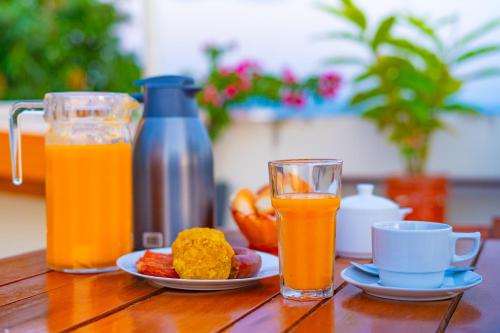 a table with a plate of food and two glasses of orange juice at Residencial Brest Amazon Tarapoto in Tarapoto