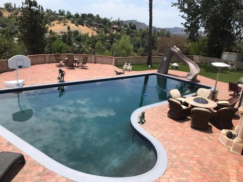 a swimming pool with a slide in a backyard at paradise luxury experience in Woodland Hills