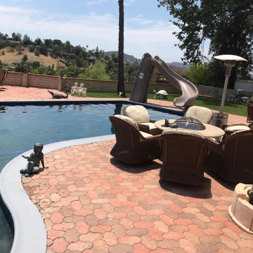 a pool with a slide and chairs next to a pool at paradise luxury experience in Woodland Hills